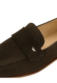 Dunkelbraune Wildleder-L loafers mit einer gesteppten Oberseite, einem erhöhten Riemen über dem Spann und einem kleinen silbernen Logo an der Seite. Glattes Leder-Innenfutter.