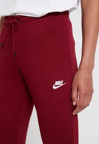 Burgunderfärgade sweatpants i mjukt tyg, med en elastisk midja och dragsnören samt en vit Nike-logga på underbenet.