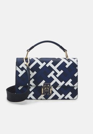 Bolso rectangular en azul marino y blanco con un audaz patrón entrelazado de letras T, herrajes dorados, asa superior y una correa para el hombro negra desmontable.