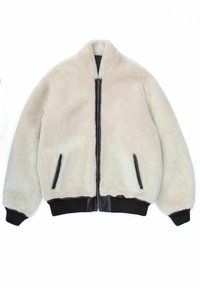 Lyse beige faux fur bomberjakke med en sort lynlås, to sidelommer og ribbede sorte manchetter og kant. Blød tekstur, afslappet design.