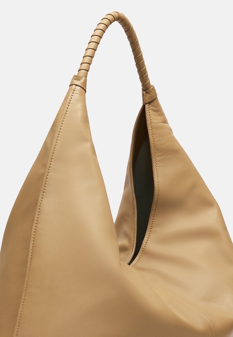 Tan leren handtas met een slouchy ontwerp, voorzien van een gevlochten handvat en een gladde textuur. Grote opening voor gemakkelijke toegankelijkheid.