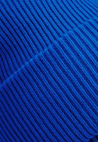 Royal blue knitted fabric with a textured pattern featuring ribbed lines, showing interwoven threads in varying shades of blue.