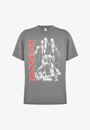 T-shirt en coton gris arborant un graphique blanc représentant une figure tenant des mains squelettiques avec des éléments de feu et d'éclairs. "Iron Maiden" est imprimé en rouge.