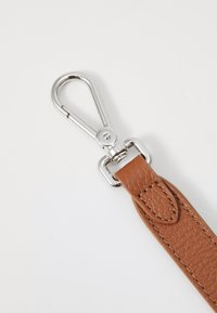 Brauner, strukturierter Lederband mit einem silbernen Metallclip am Ende, der über einen Drehmechanismus für eine einfache Befestigung verfügt.