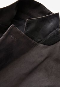 Collare in pelle scamosciata nera con una texture liscia, caratterizzato da un tessuto interno a contrasto. Design minimalista con dettagli di cucitura sottili.