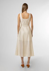 Lenové midi šaty světle béžové barvy se čtvercovým výstřihem na zádech a páskem v pase. Plynulý střih, hladká textura a jemný lesk.