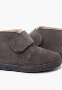 Scarpe grigie in suede con strap in velcro, punta arrotondata e suola in gomma texture. Fodera interna morbida per il comfort. Design a basso profilo.