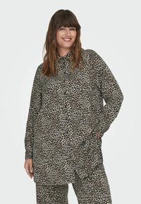 Leopardų rašto mygtukų š shirtas su ilgomis rankovėmis, pagamintas iš minkštos medžiagos; turi apykaklę ir kišenes, derinamas su atitinkančiomis kelnėmis.