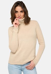 Beige Rollkragenpullover mit gerippter Textur und langen Ärmeln, der eine lässige Passform sowie eine subtile Nahtdetails am Kragen aufweist.