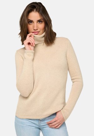 Pull en col roulé beige avec une texture à côtes et des manches longues, présentant une coupe décontractée et un détail de couture subtil au niveau du col.