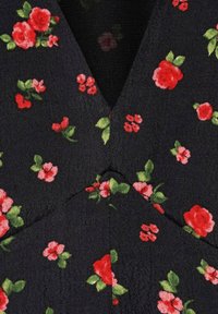 Blumiger Stoff mit roten und pinken Blumen sowie grünen Blättern auf schwarzem Hintergrund; strukturierter Gewebeaufbau mit einem V-Ausschnitt-Detail.