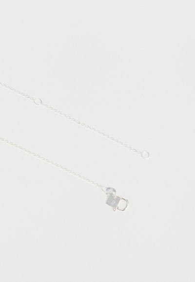 Chaîne délicate en argent avec un petit fermoir en forme de cadenas gravé du poinçon "925" sur fond blanc.