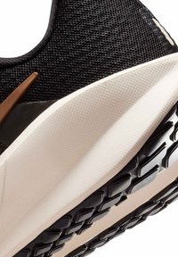 Czarny but sportowy z teksturowaną siateczkową cholewką, brązowym akcentem oraz grubą, kremową podeszwą środkową. Podeszwa zewnętrzna ma wzorzysty bieżnik zapewniający przyczepność.
