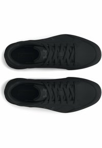 Baskets de sport noires avec une tige synthétique lisse, fermeture à lacets plate et un marquage minimal sur la languette et les côtés. Semelle texturée pour un confort optimal.