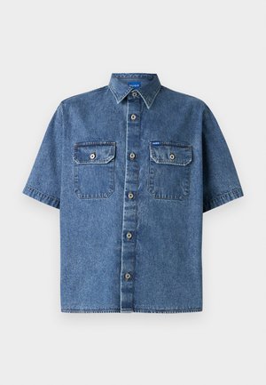 Camisa de denim de manga corta en azul medio. Cuenta con un collar puntiagudo, dos bolsillos en el pecho y un cierre frontal con botones y acentos metálicos. Textura suave.