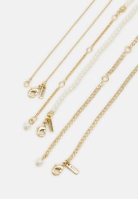 Conjunto de joyería en tono dorado que presenta múltiples cadenas, eslabones lisos y texturizados, con acentos de perlas y cierres de langosta.