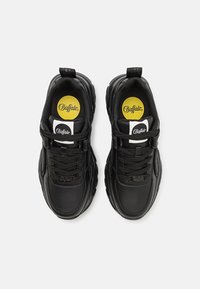 Black sneakers with a smooth leather upper, thick rubber sole, and black laces. Features yellow and white branded insoles.