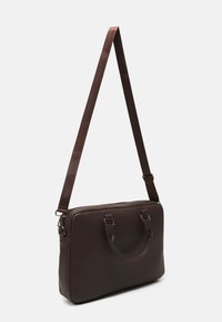 Sac en cuir marron texturé avec deux poignées courtes et une longue sangle réglable. Fermeture zippée et accents en métal. Forme rectangulaire.