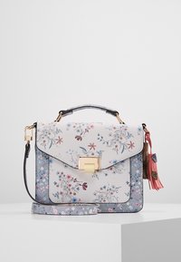 Floral-patterned handbag with blue and white panels, gold clasp, top handle, detachable strap, and pink tassel charm on white surface.