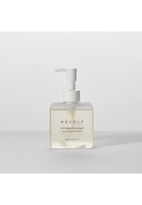 Bottiglia quadrata trasparente con erogatore a pompaggio bianco. Contiene olio detergente di colore giallo chiaro. L'etichetta riporta "NEEDLY Mild deep cleansing oil."