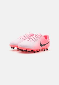 Rosa fotballsko med en gradient hvit finish, svart Nike-swoosh, teksturert overdel og svarte pigger på sålen for grep.