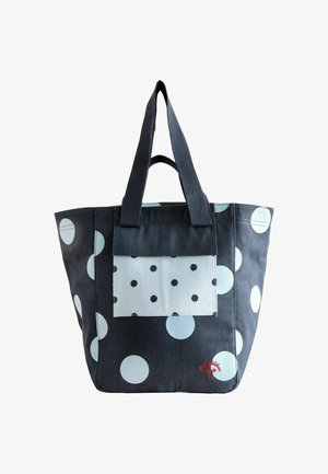 Geantă din canvas cu buline mari albastre și albe, având o buzunar frontal cu un design mai mic de buline și detalii brodate roșii.