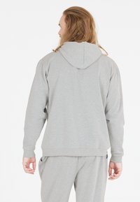 Szary kaptur z regulowanym ściągaczem, prążkowymi mankietami oraz luźnym krojem. Wykonany z miękkiego materiału, z bocznymi kieszeniami i prostym designem.