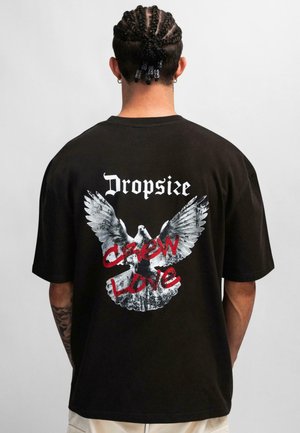 Black cotton t-shirt with oversized fit, featuring a large white eagle graphic and red text "CREW LOVE" on the back.