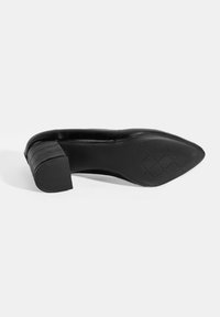 Zwarte pointed-toe schoen van een gestructureerd synthetisch materiaal, met een lage blokhak en een gepatternde zool met een kruislings ontwerp.