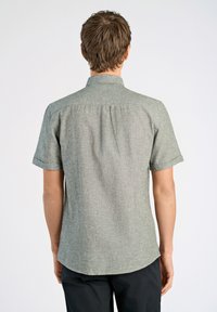 Korte mouwen shirt in een lichtgroene, textuurstof, met een kraag en een gebogen zoom. Een rugplooidetail voegt structuur toe.