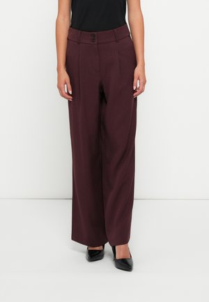 Bordeaux brede buks med høj talje, der har to knapper og fodfolder; stoffet har en glat tekstur. Båret med sorte sko.