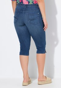 Tumman denim-kaprisilmukat, joissa on joustava vyötärö, takataskut ja sivuhihojen halkiot helmaosassa. Rakenteellinen kangas, jossa on sileä pinta.