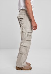 Pantalones cargo beige con múltiples bolsillos laterales y lazos para cinturón. Fabricados con una tela duradera, presentan un diseño de pierna recta y un ajuste relajado.
