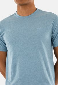 Light blue short-sleeve T-shirt with a crew neck, made of soft cotton blend fabric, featuring a subtle embroidered logo on the chest.