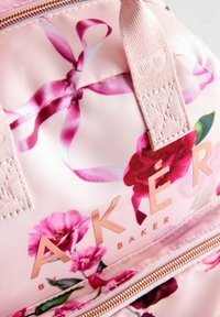 Borsa in tessuto con motivo floreale rosa e accenti rosa chiaro, con logo e zip in oro rosa. Nastri e fiori aggiungono dettagli decorativi.