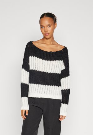 Maglione a righe bianche e nere, texture a costine, ampia scollatura a spalle scoperte, maniche lunghe, con una vestibilità morbida.