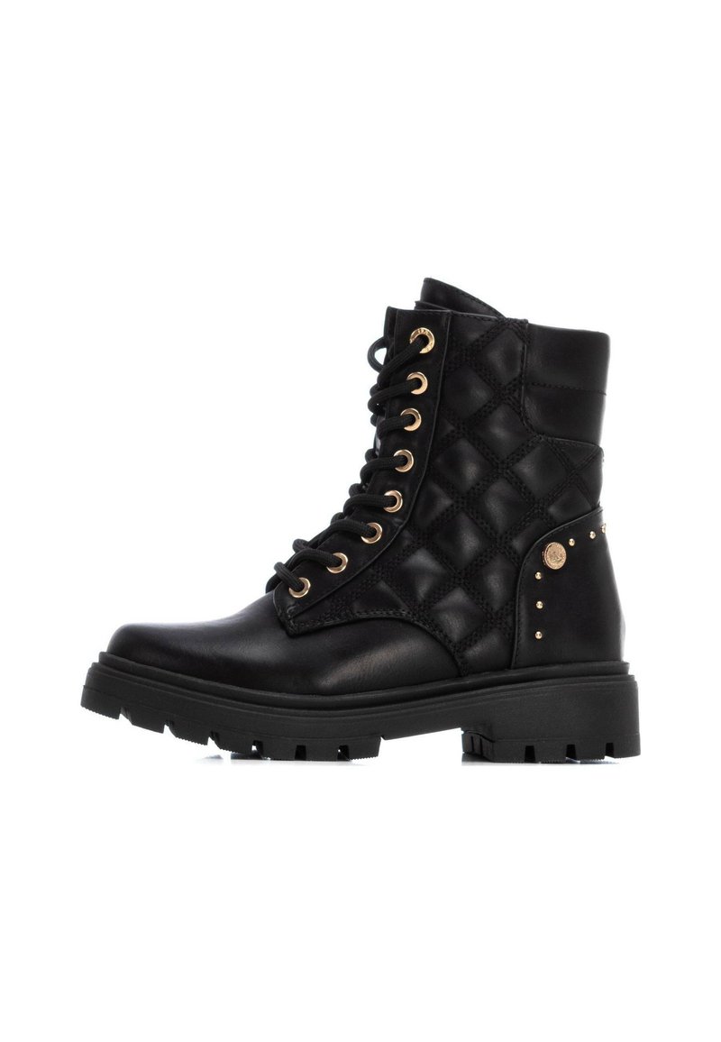 Botines negros de tobillo hechos de cuero suave y material acolchado texturizado, con ojales dorados, tachuelas y una suela robusta.