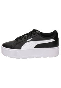 Baskets synthétiques noires avec accents blancs, bout arrondi, semelle plate à plateforme et design à lacets. Logo PUMA affiché sur le côté.