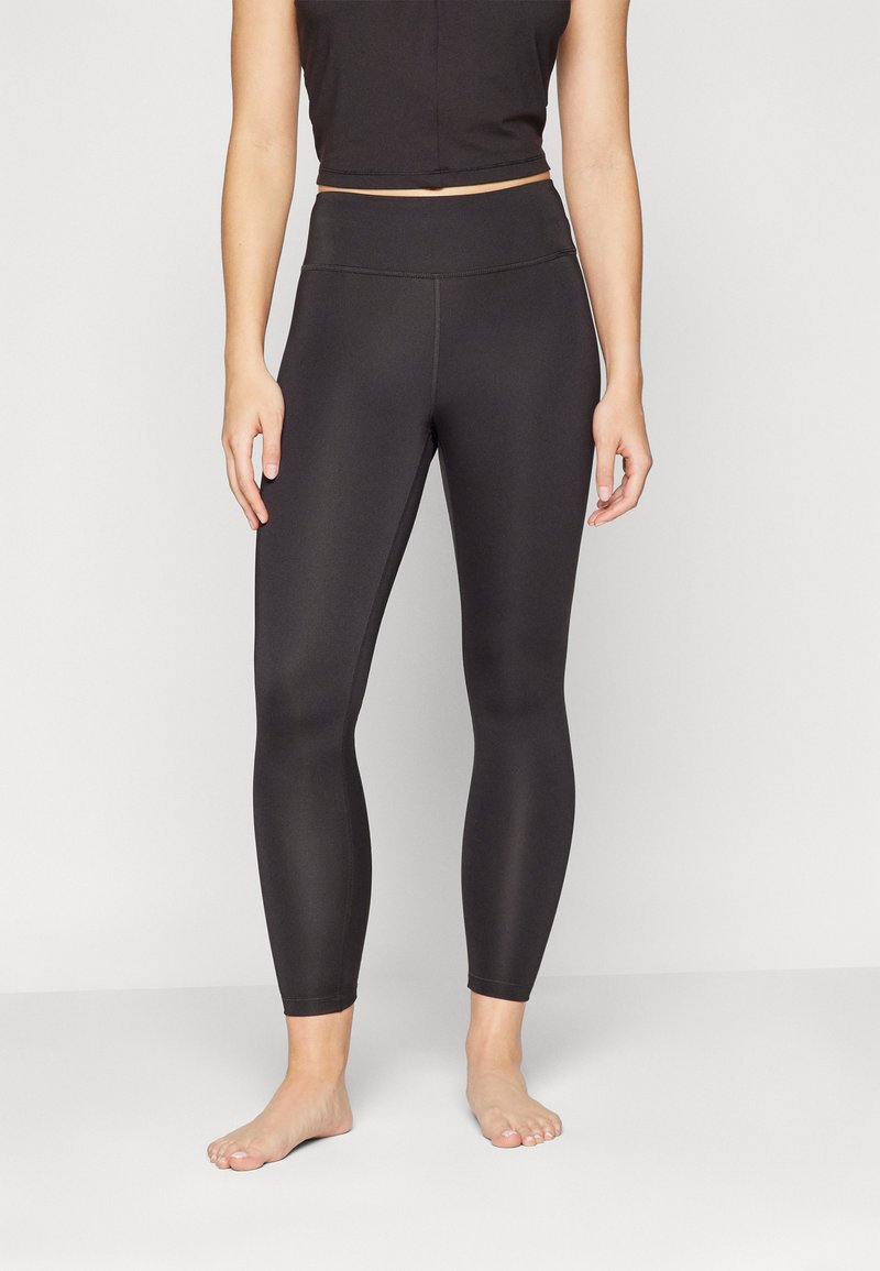 Black leggings with a high waistband, made of stretchy, smooth fabric. Features a fitted design, seamless sides, and no visible hardware.