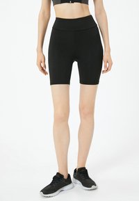 Pantalones cortos de bicicleta negros de tiro alto con una textura suave, diseño ajustado y una cinturilla ancha. Adecuados para ropa de deporte.