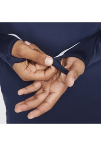 Marineblauw longsleeve shirt met duimsgaten in de mouwen; soepel, rekbaar materiaal; close-up van handen die de manchetten van de mouwen aanpassen.