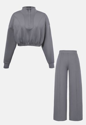 Hall toonikomplekt, mis koosneb lühikesest ees tõmblukuga pusa-ülaosast ja elastse äärega, mida täiendab kõrge vöökoht ja laiade säärtega püksid.