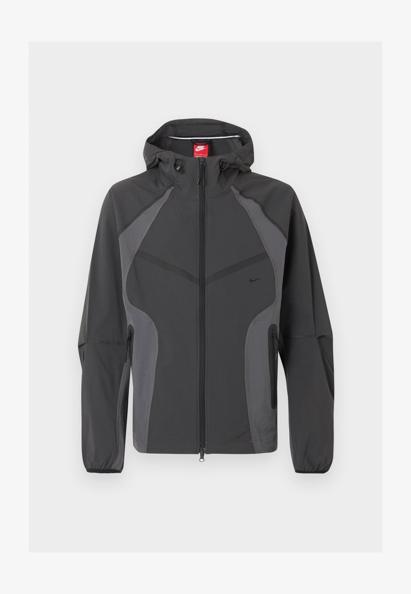 Dunkelgraue Nike Kapuzenjacke mit durchgehendem Frontreißverschluss, seitlichen Reißverschlusstaschen und elastischen Bündchen, dargestellt vor weißem Hintergrund.