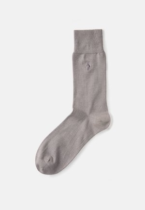 Calzino in cotone grigio con un bordo a costine e una trama liscia. Presenta un piccolo logo ricamato vicino alla caviglia.