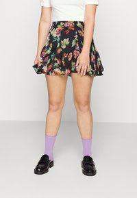 Floral black mini skirt with pleated design, featuring colorful flower patterns. Paired with lavender ribbed socks and black loafers.