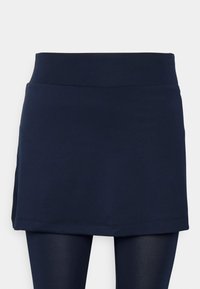 Mörkblå kjol med slät textur, utrustad med en bred midjeresår och en rak skärning. Designad för att bäras ovanpå leggings.