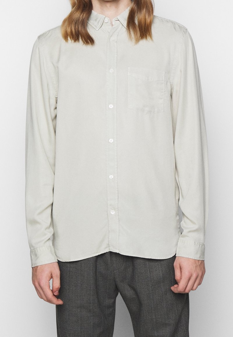 Camicia grigia chiara con bottoni realizzata in cotone, dotata di taschino sul petto, colletto alla francese e maniche lunghe con polsini abbottonati.