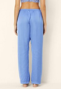Pantaloni de pijama din satin de culoare albastru deschis, cu talie elastică, picioare drepte și o textură netedă. Fără modele vizibile sau detalii metalice.