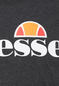 Tissu foncé avec des lettres minuscules blanches «esse» et un logo en demi-cercle au-dessus, comportant des segments orange et rouges sur un fond blanc.