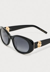 Μαύρα οβάλ γυαλιά ηλίου με σκούρες φακούς, χρυσές λεπτομέρειες με το λογότυπο "B" στους βραχίονες και τη σήμανση "BOSS" στην εσωτερική πλευρά του δεξιού βραχίονα.